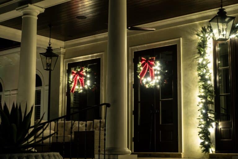 Illuminated Christmas wreaths and lights decorating the entrance to a house